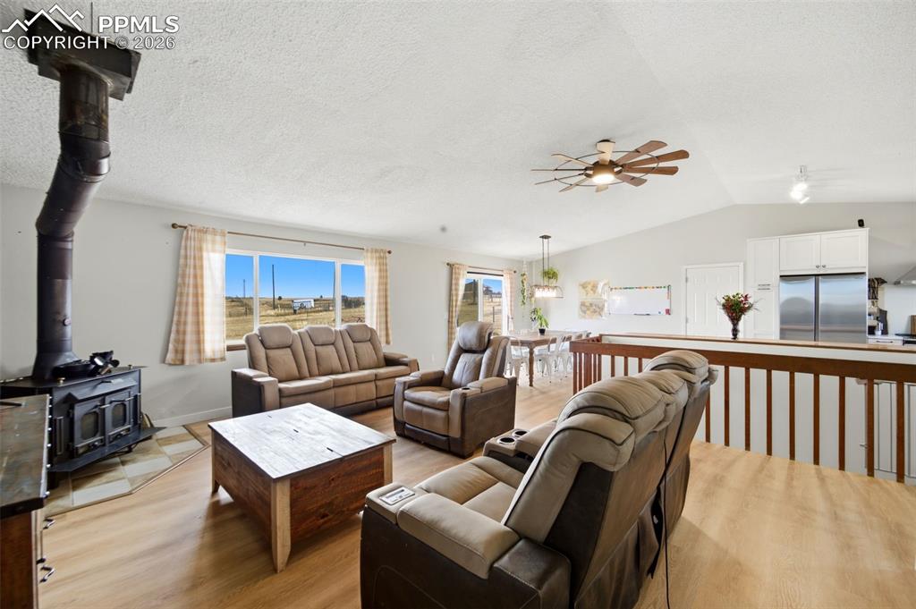 Image 10 of 37: Living room with a wood stove, ceiling fan, light wood finished floors, lof