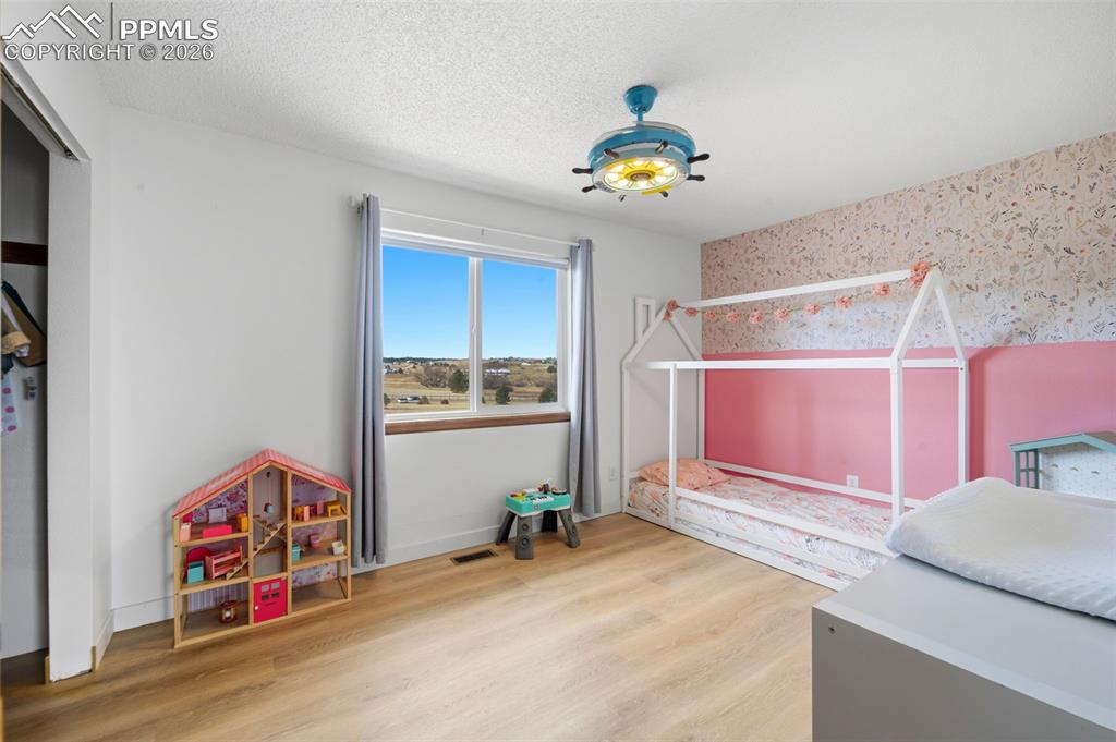 Image 15 of 37: Bedroom with a textured ceiling, light wood-type flooring, and wallpapered 
