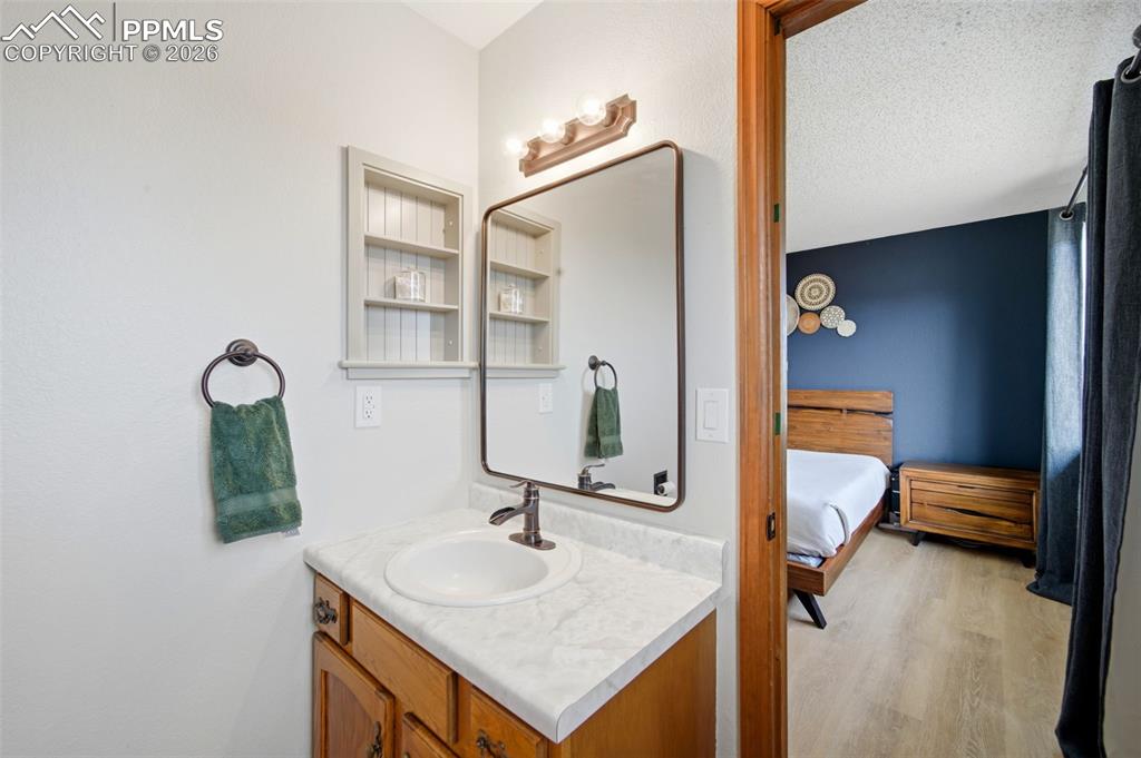 Image 18 of 37: Ensuite bathroom with vanity, light wood-type flooring, and a textured ceil