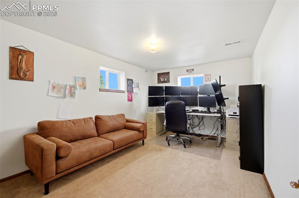 Image 23 of 37: Office area with light colored carpet and plenty of natural light