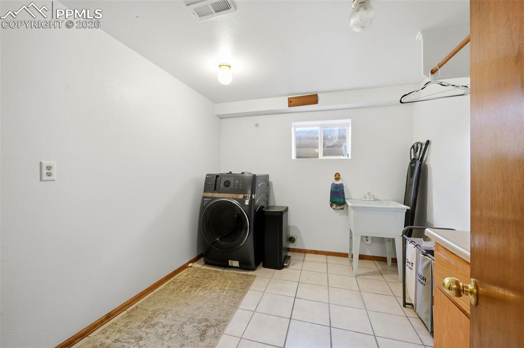 Image 27 of 37: Laundry area with washer / clothes dryer and light tile patterned floors