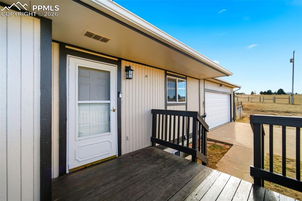 Image 4 of 37: Entrance to property featuring a garage, driveway, and a deck