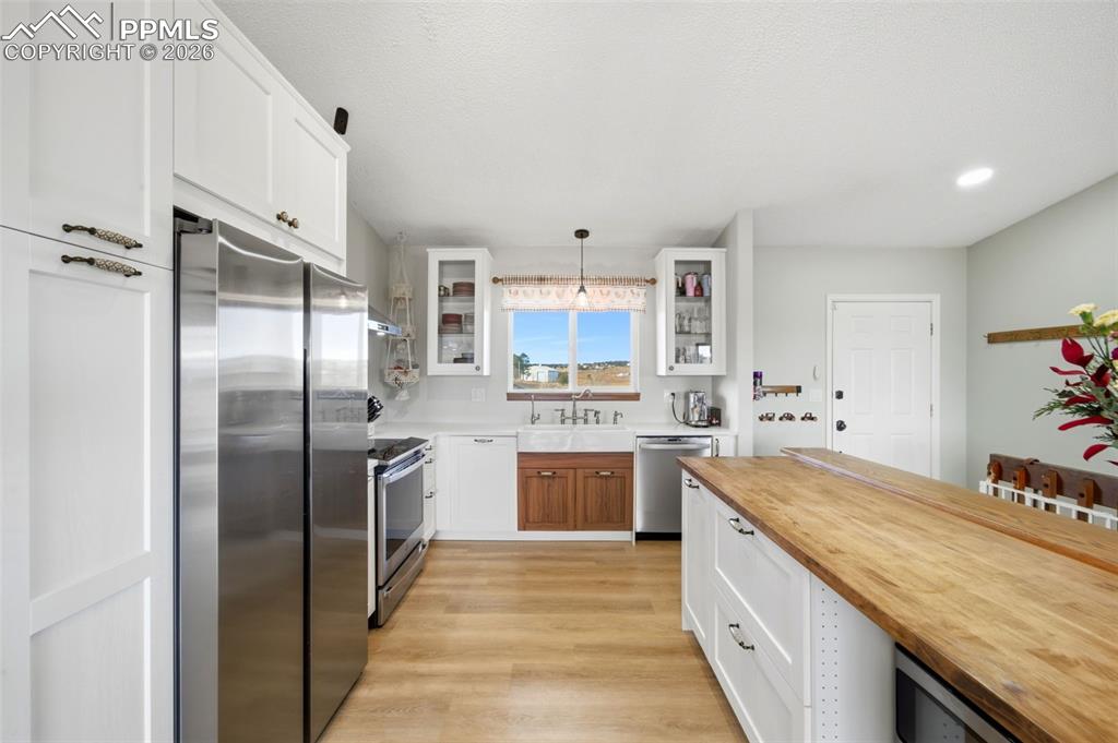 Image 7 of 37: Kitchen featuring white cabinetry, butcher block counters, appliances with 