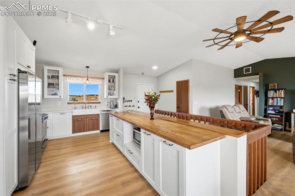 Image 8 of 37: Kitchen with white cabinetry, glass insert cabinets, wooden counters, ceili