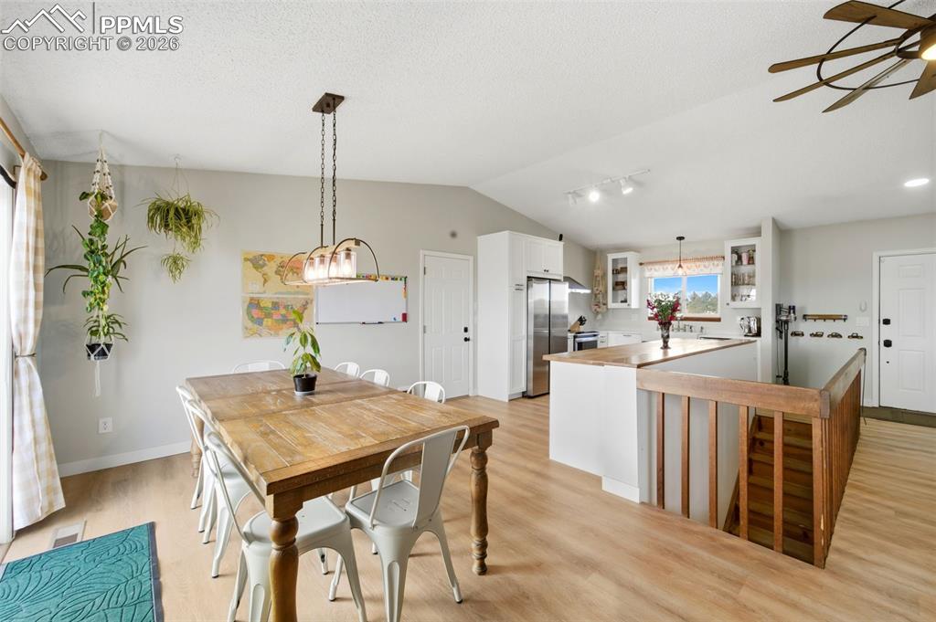Image 9 of 37: Dining space featuring lofted ceiling, light wood-style floors, a textured 