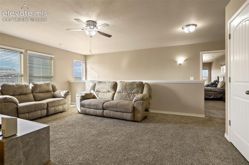 Image 10 of 30: Carpeted living area featuring a ceiling fan with integrated lighting, mult
