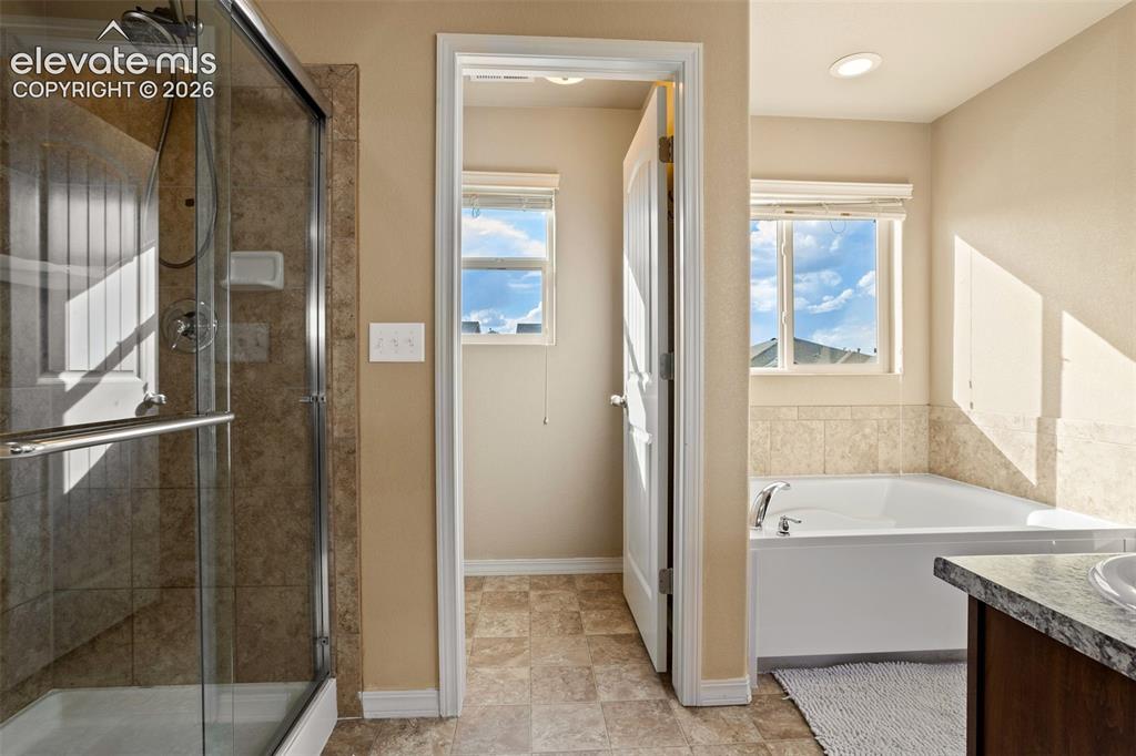 Image 16 of 30: Full bathroom featuring a glass-enclosed shower, a built-in bathtub with ti