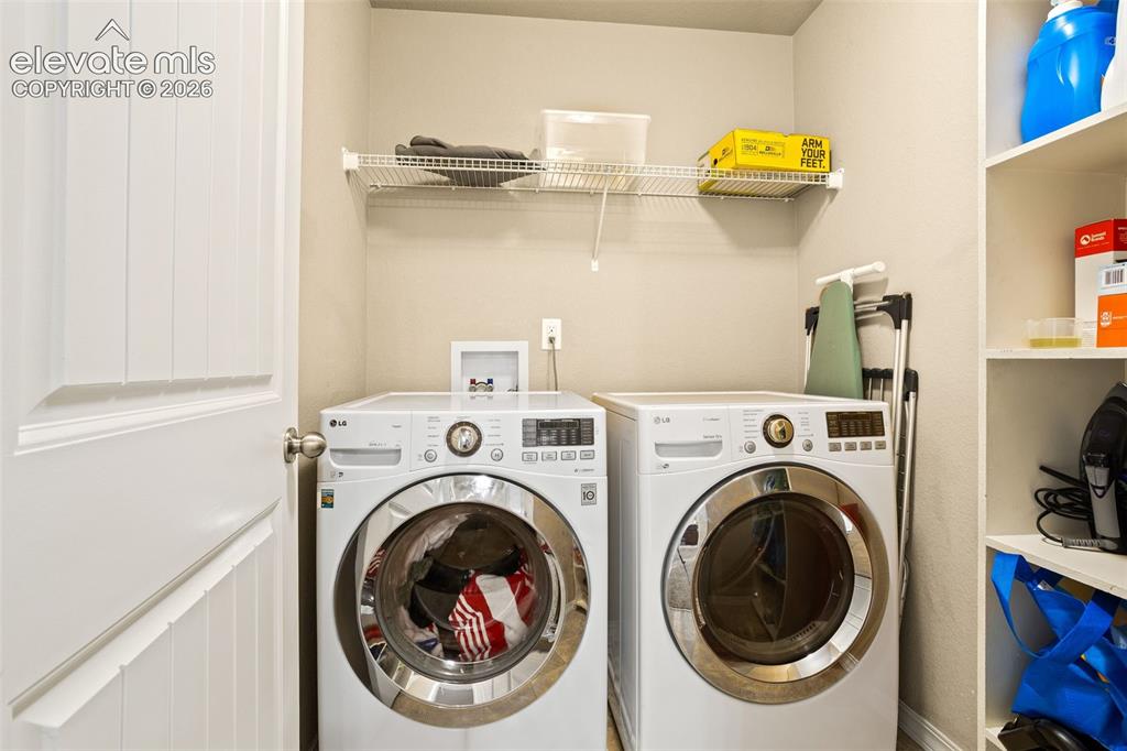 Image 19 of 30: Laundry area with white paneled door, wire shelving, and built-in shelving