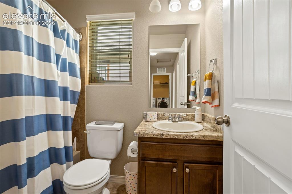 Image 22 of 30: Bathroom featuring a single vanity with a built-in sink, stone-finish count