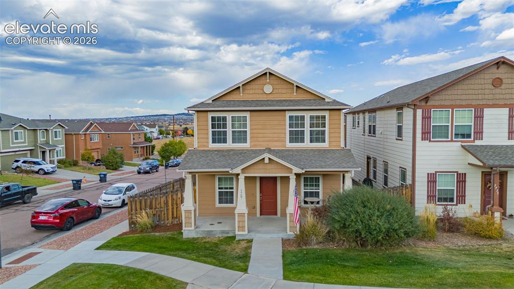 Image 25 of 30: Two-story residence with a covered front porch and red entry door
