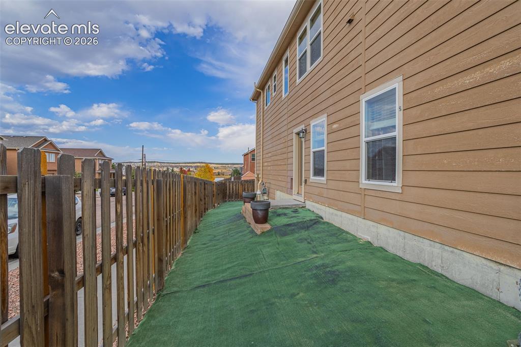 Image 28 of 30: Wood-siding exterior with multiple windows and a private wooden fence