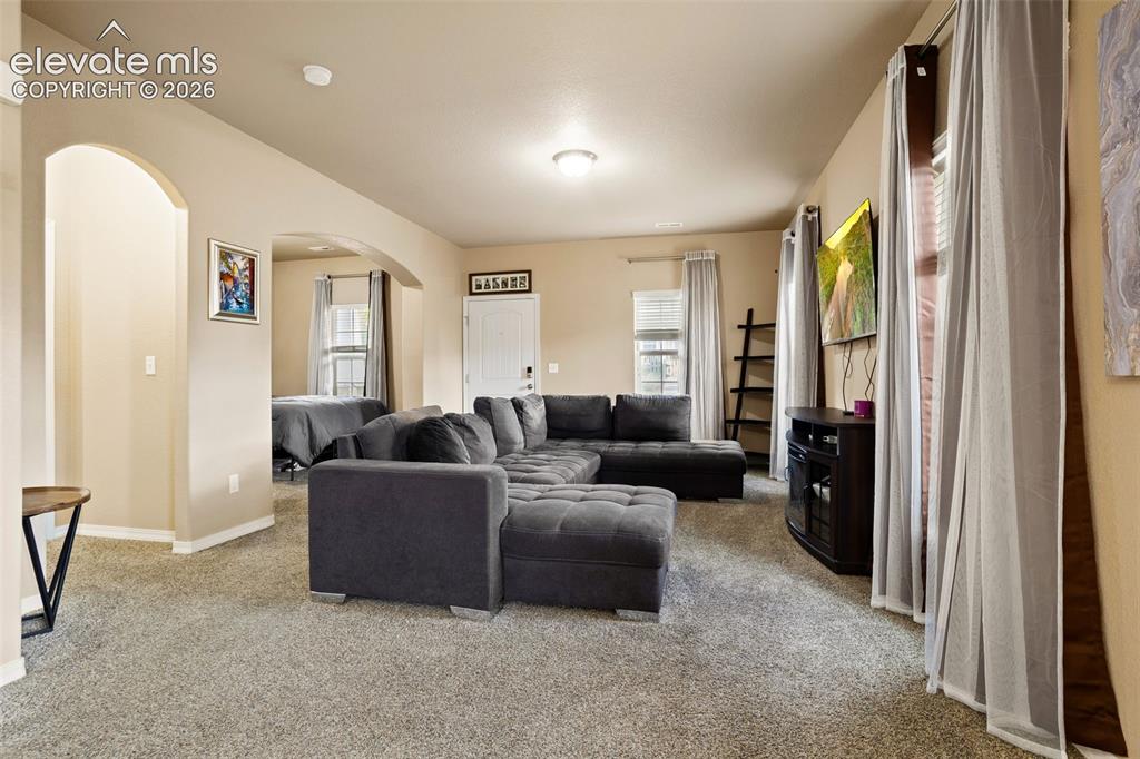 Image 3 of 30: Carpeted living area with arched doorways and neutral wall tones