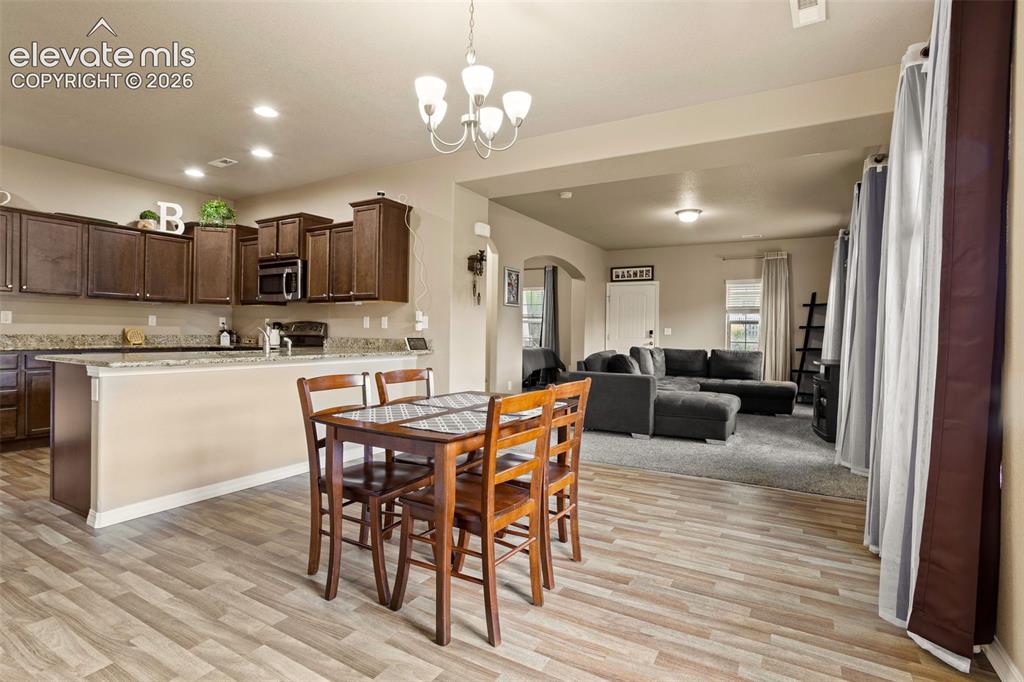 Image 5 of 30: Open-concept living area with wood-finish flooring, recessed lighting, and
