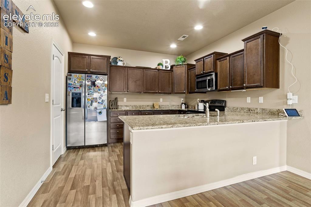 Image 6 of 30: Kitchen featuring dark wood-finish cabinetry, granite-style countertops, st