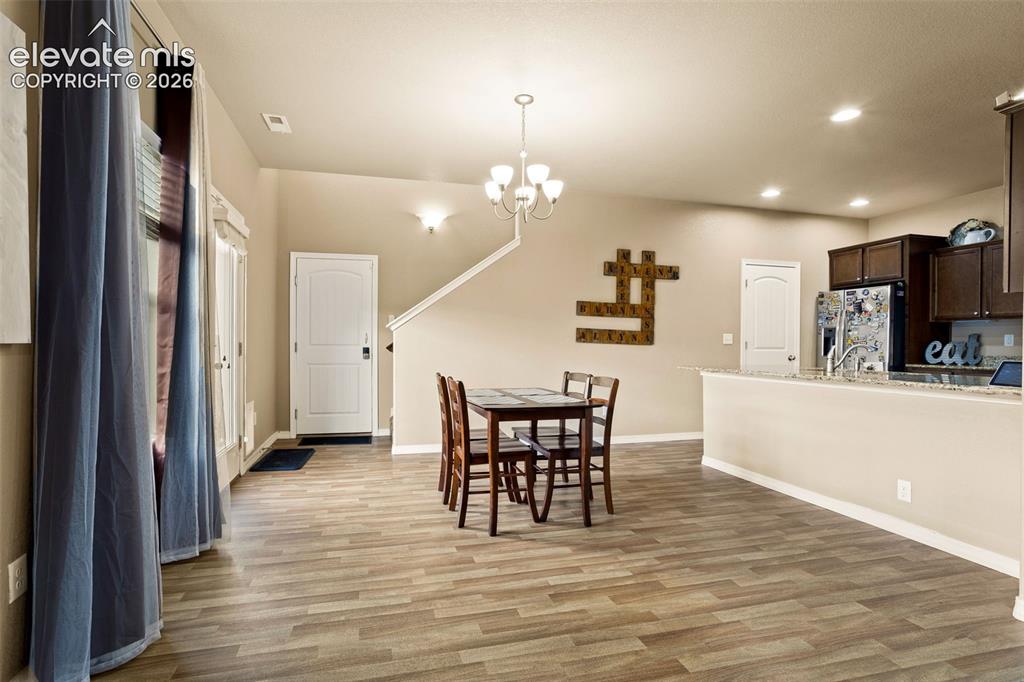 Image 8 of 30: Wood-finish flooring throughout, recessed lighting, and a chandelier illumi