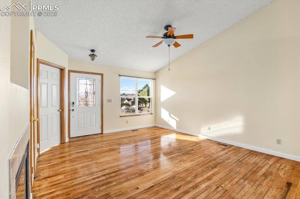 Image 10 of 27: Entryway featuring a textured ceiling, light wood-type flooring, vaulted ce