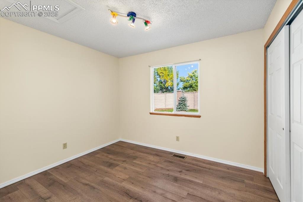 Image 13 of 27: Unfurnished bedroom with a closet, dark wood-style floors, and a textured c
