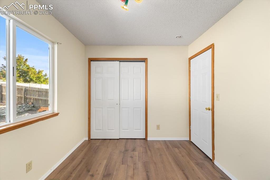 Image 14 of 27: Unfurnished bedroom with wood finished floors, a closet, and a textured cei