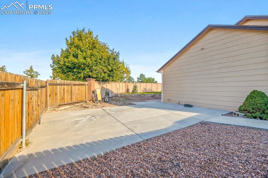 Image 19 of 27: Fenced backyard with a patio