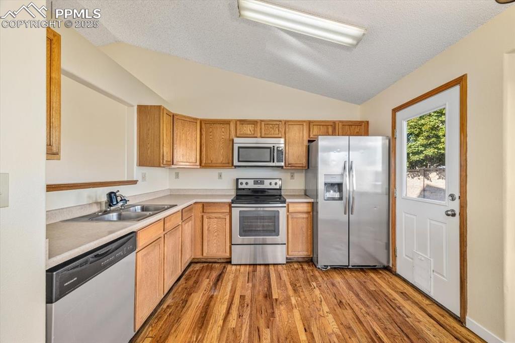 Image 5 of 27: Kitchen featuring stainless steel appliances, dark wood-style flooring, lig