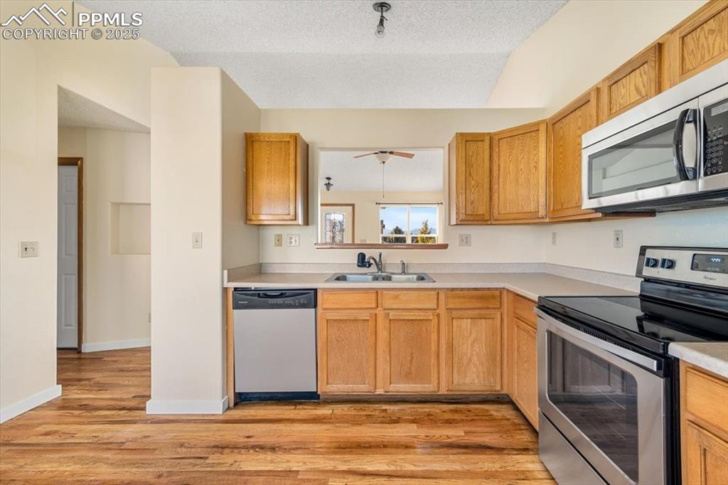 Image 6 of 27: Kitchen with stainless steel appliances, light countertops, a textured ceil