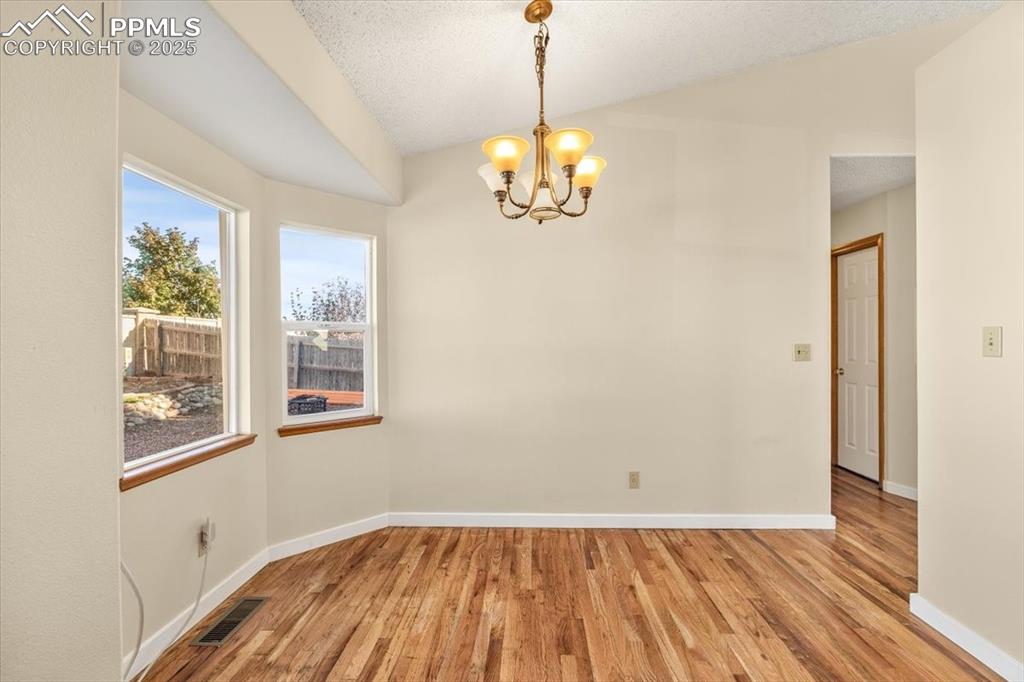 Image 7 of 27: Unfurnished dining area featuring light wood-type flooring, lofted ceiling,