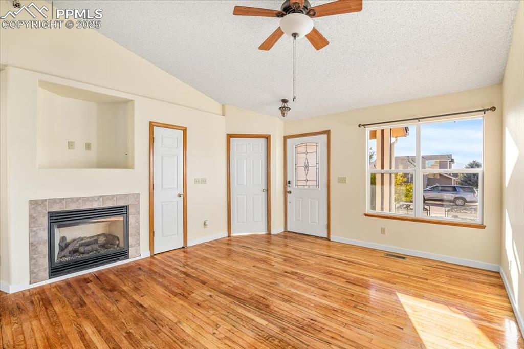 Image 8 of 27: Unfurnished living room featuring light wood-style floors, a tile fireplace