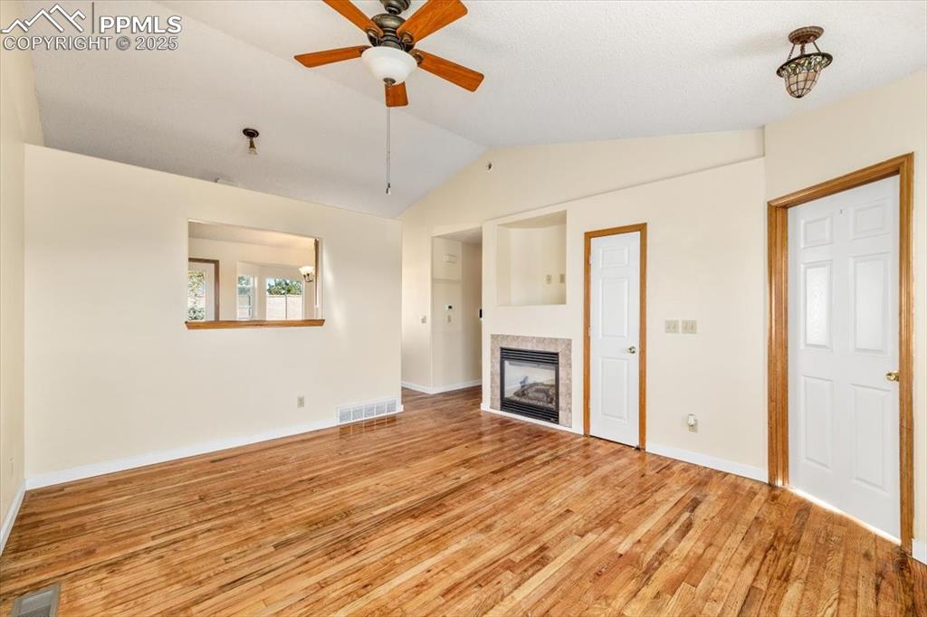 Image 9 of 27: Unfurnished living room featuring vaulted ceiling, light wood-style floorin