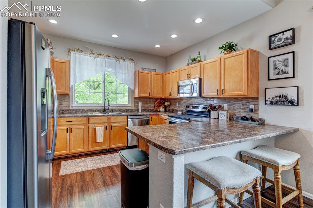 Image 10 of 32: Kitchen with new faucet, maple cabinets, and tiled backsplash.