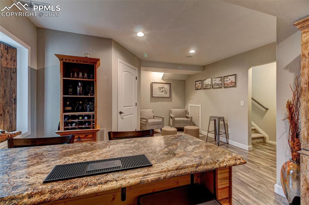 Image 18 of 32: Rec room has laminate wood floors and a wet bar.