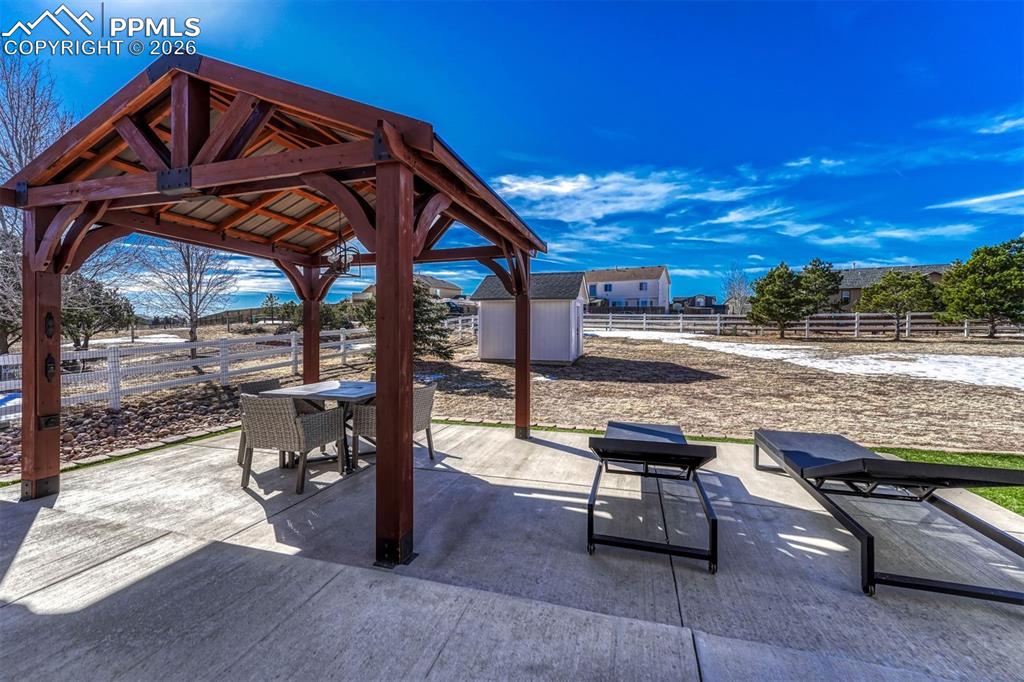 Image 35 of 42: The extended back patio steps down to a covered pergola, creating a relaxin