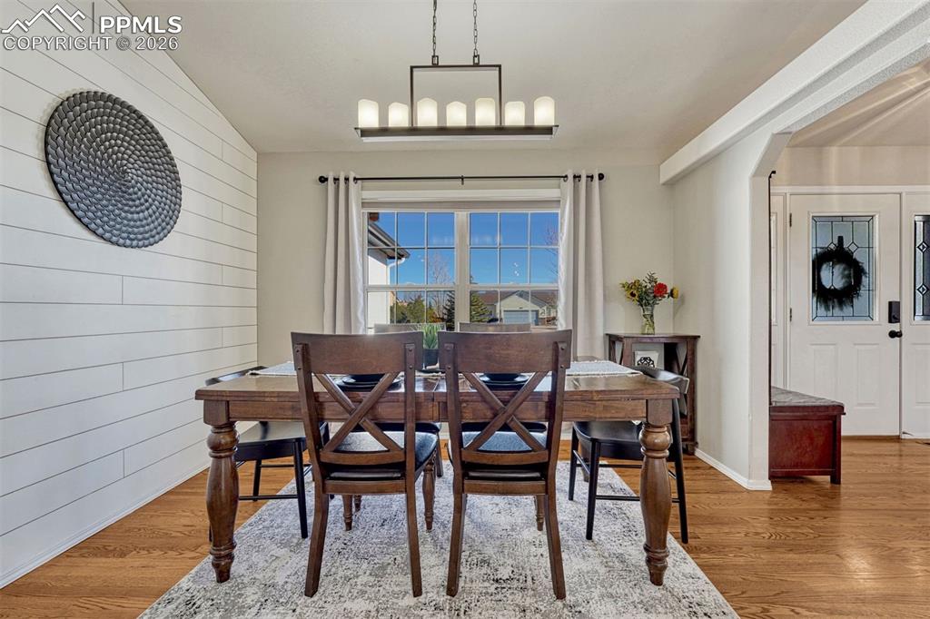 Image 9 of 42: The dining room features modern lighting and a decorative shiplap accent wa