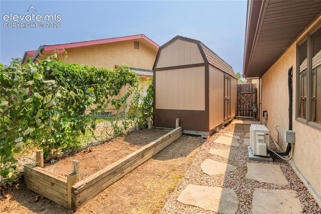 Image 22 of 50: Private side yard features a raised garden bed, storage shed, and a crushed