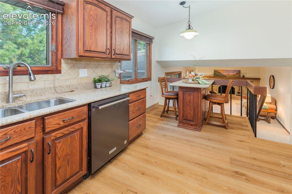 Image 23 of 50: Back inside, the kitchen features new LVP flooring, wood cabinetry, granite
