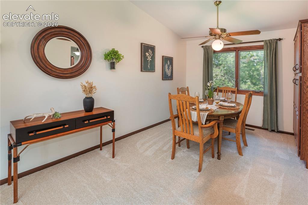 Image 27 of 50: Dining area featuring a window with green outdoor scenery, a ceiling fan wi