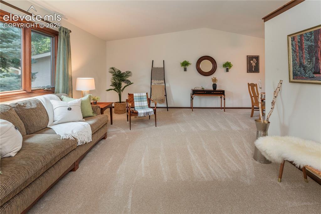 Image 28 of 50: Spacious living area with brand new carpet, a vaulted ceiling, and awning-s
