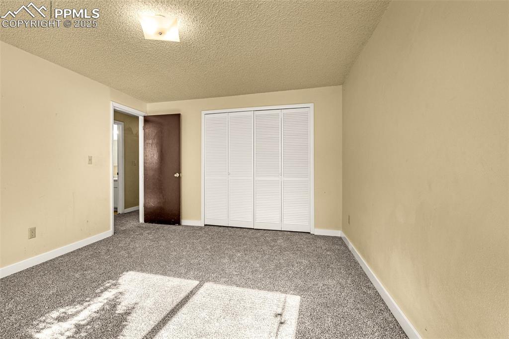 Image 10 of 15: Unfurnished bedroom featuring carpet flooring, a textured ceiling, and a cl