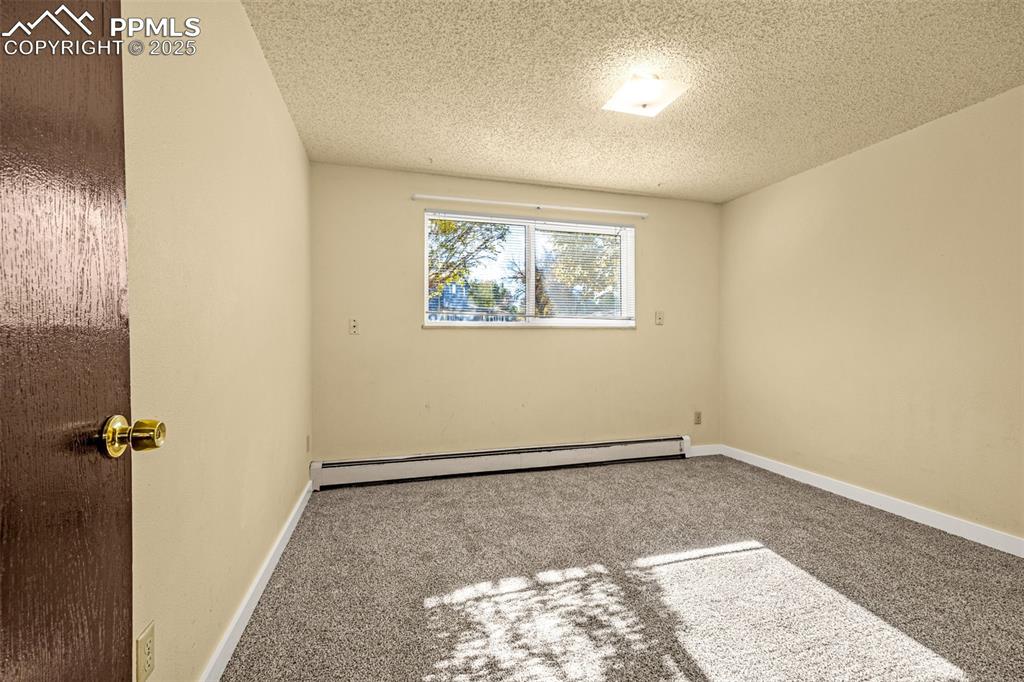 Image 12 of 15: Spare room with carpet floors, a baseboard heating unit, and a textured cei