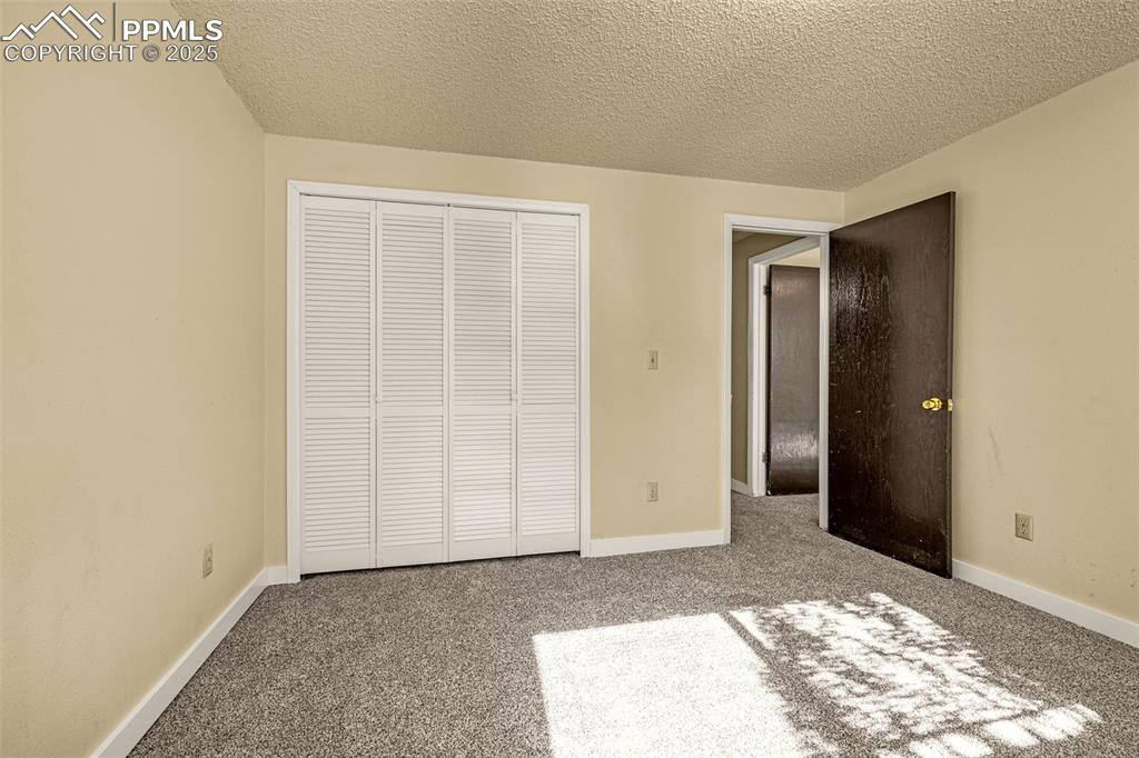 Image 13 of 15: Unfurnished bedroom featuring carpet floors, a textured ceiling, and a clos