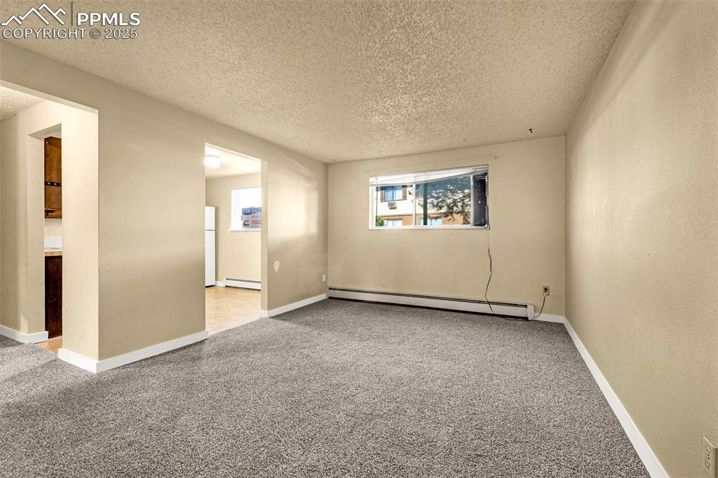 Image 4 of 15: Unfurnished room featuring light colored carpet, a baseboard radiator, and