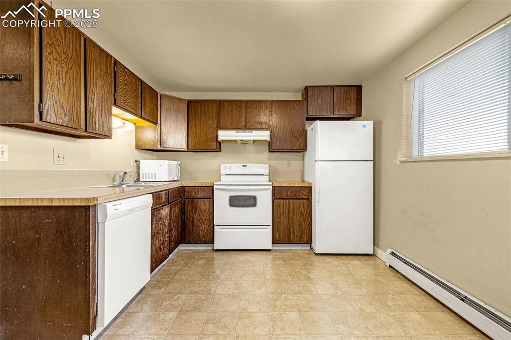 Image 6 of 15: Kitchen with a baseboard radiator, white appliances, light countertops, and