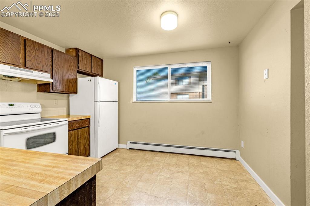 Image 7 of 15: Kitchen with white appliances, light countertops, under cabinet range hood,