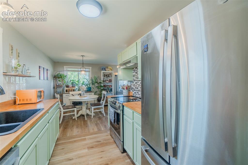 Image 11 of 31: Kitchen featuring light green cabinetry, wood-finish countertops, and stain