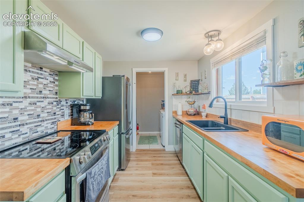 Image 13 of 31: Kitchen featuring mint green cabinetry, wood-finish countertops, stainless