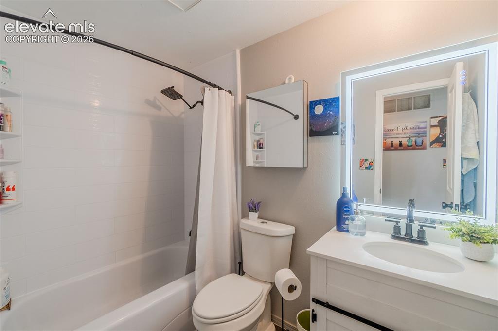 Image 16 of 31: Bathroom vanity with white countertop, undermount sink, and dark-finish fau