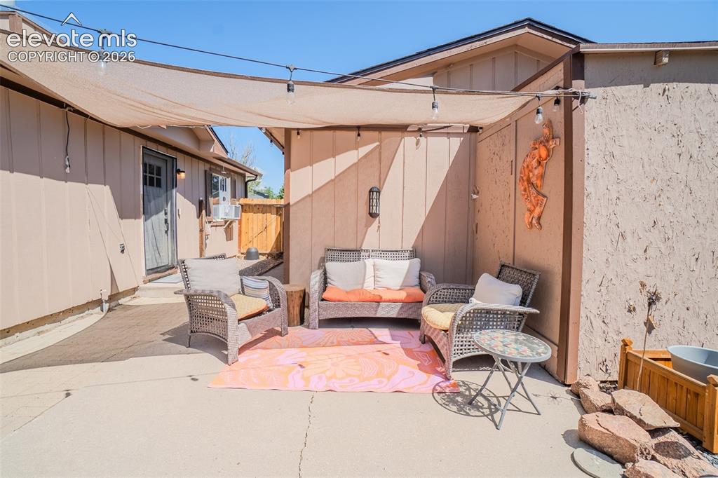 Image 25 of 31: Paved patio area featuring a shade sail with string lighting, exterior wall