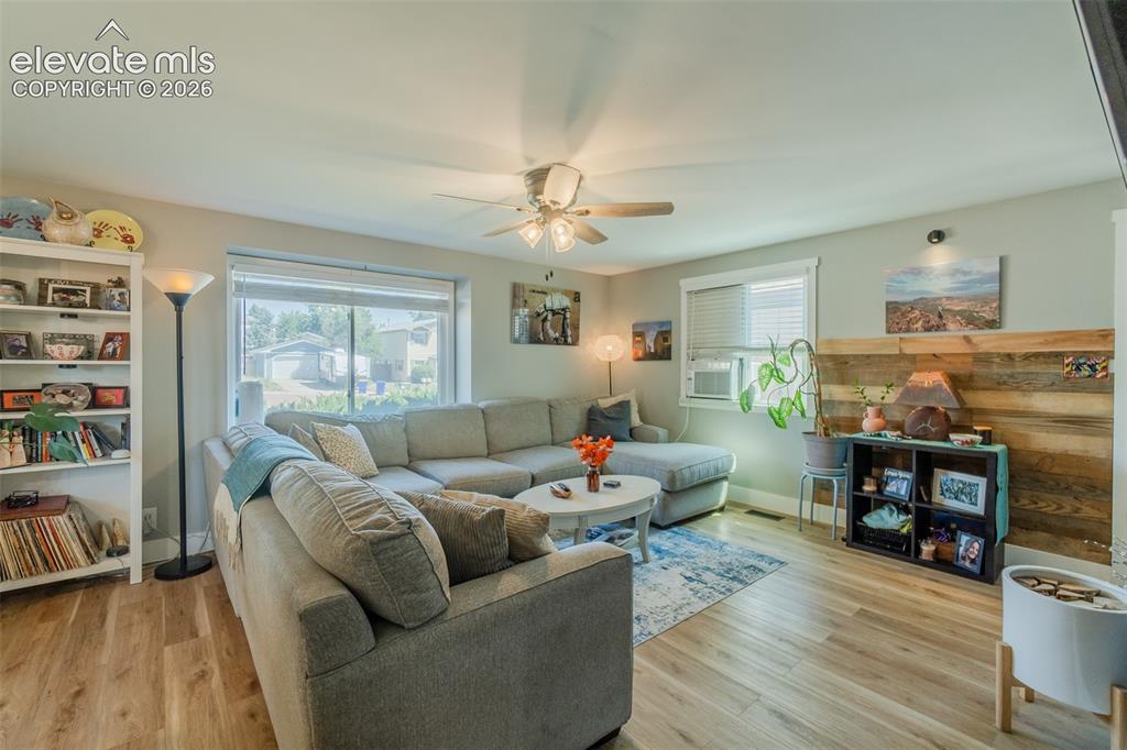 Image 3 of 31: Spacious living area featuring wood-finish flooring, a ceiling fan with int