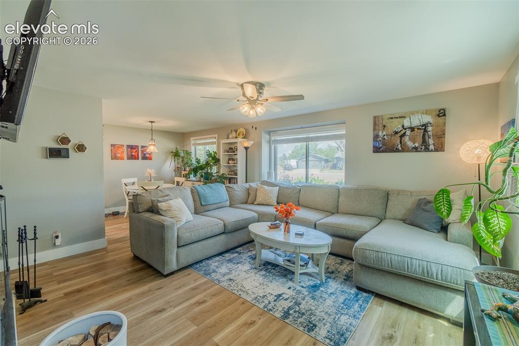 Image 4 of 31: Open-concept living area featuring wood-finish flooring, a ceiling fan with