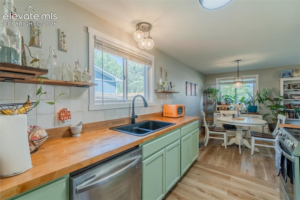 Image 5 of 31: Kitchen featuring butcher block countertops, light green cabinetry, a stain