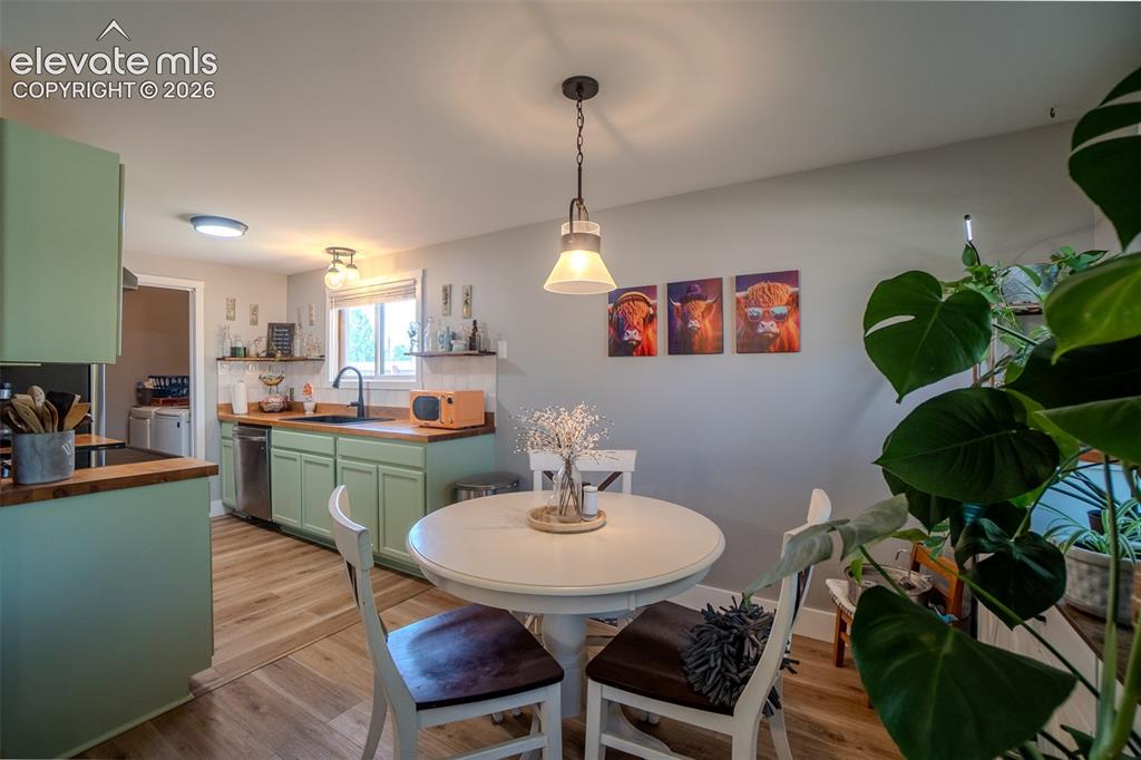 Image 8 of 31: Open-concept kitchen featuring light green cabinetry with wood countertops,